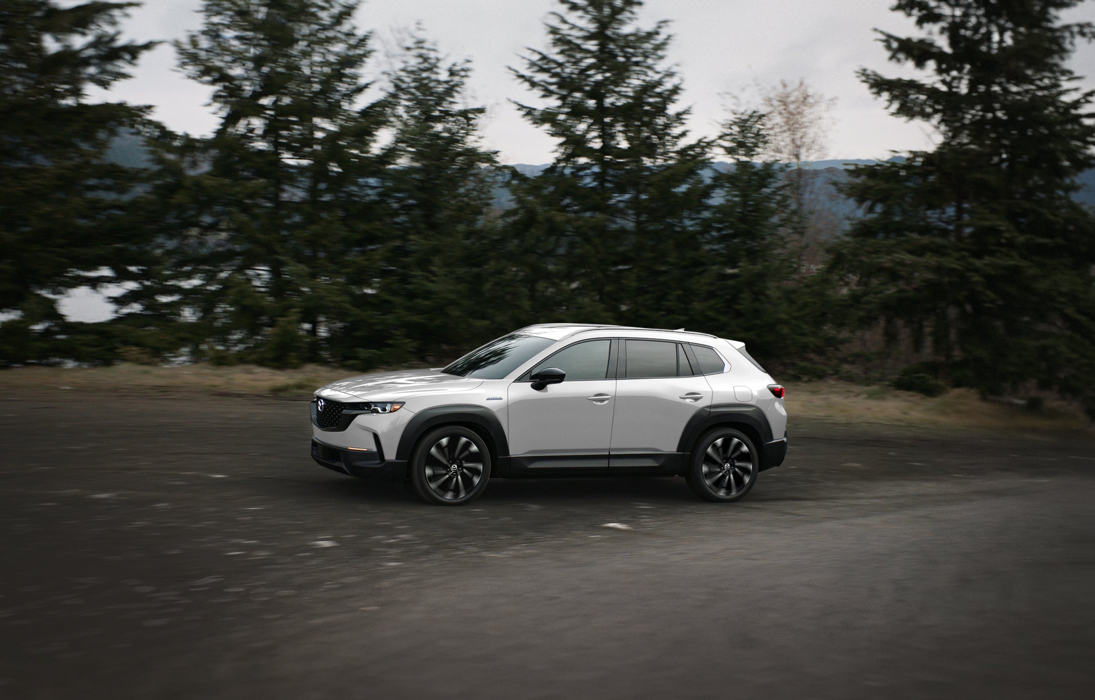 A new Mazda vehicle driving through a forested road