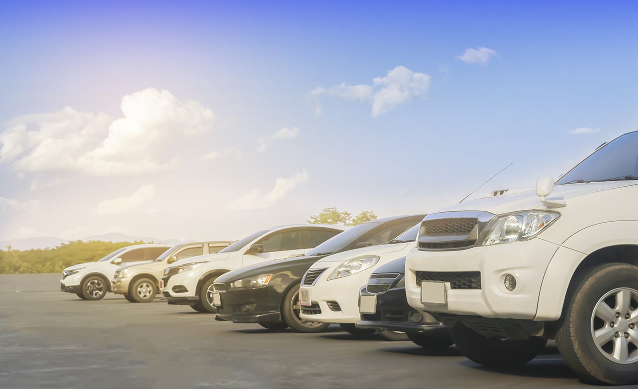 Car parked in large asphalt parking lot with white cloud and blu