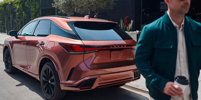 An all new orange Lexus RX parked on a downtown city street. - Lexus of Huntsville, AL
