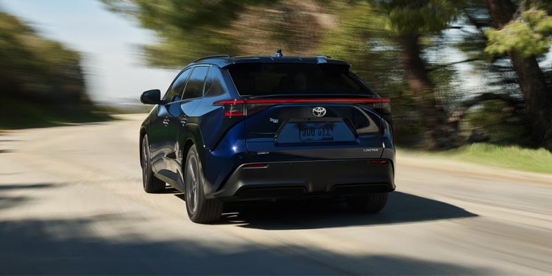 Blue Toyota SUV driving on a road with motion blur and trees in the background.