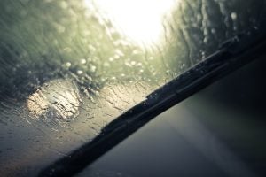 car wiper blade wiping away rain from front windshield