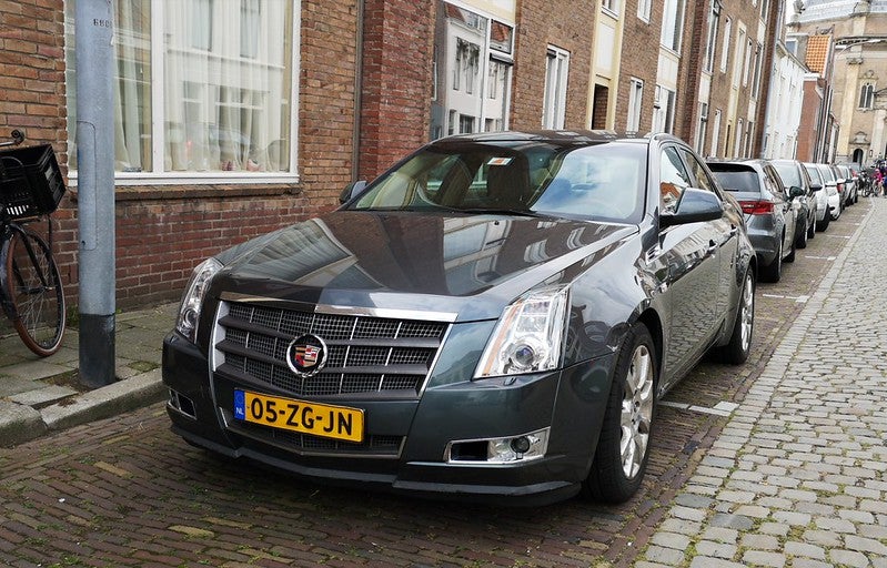 Black Cadillac parked on a cobblestone street