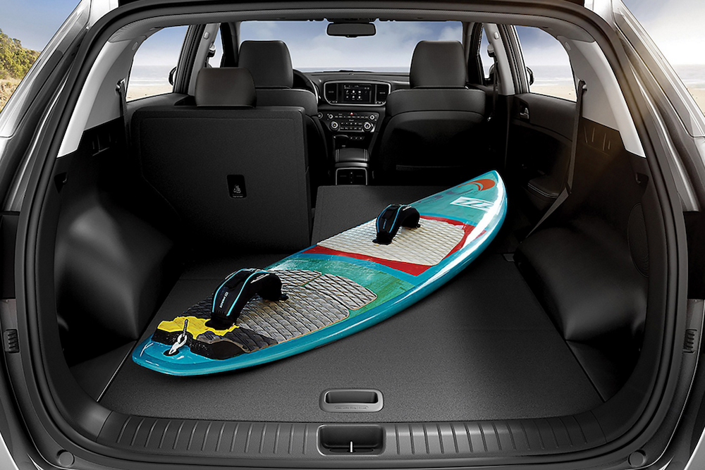 A Stuart Florida driver puts a full sized surfboard inside the back of a 2022 KIA Sportage.