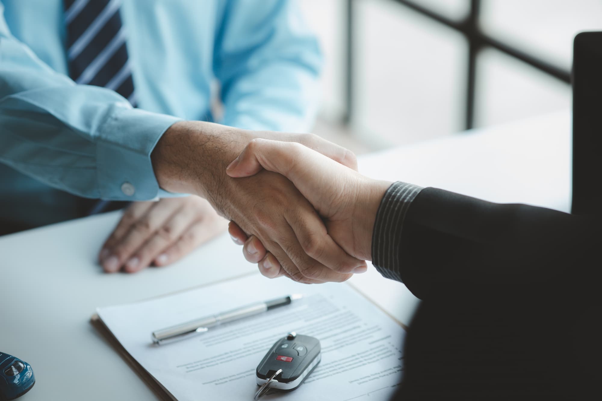 customer and sales rep at a dealership shaking hands for a car trade in