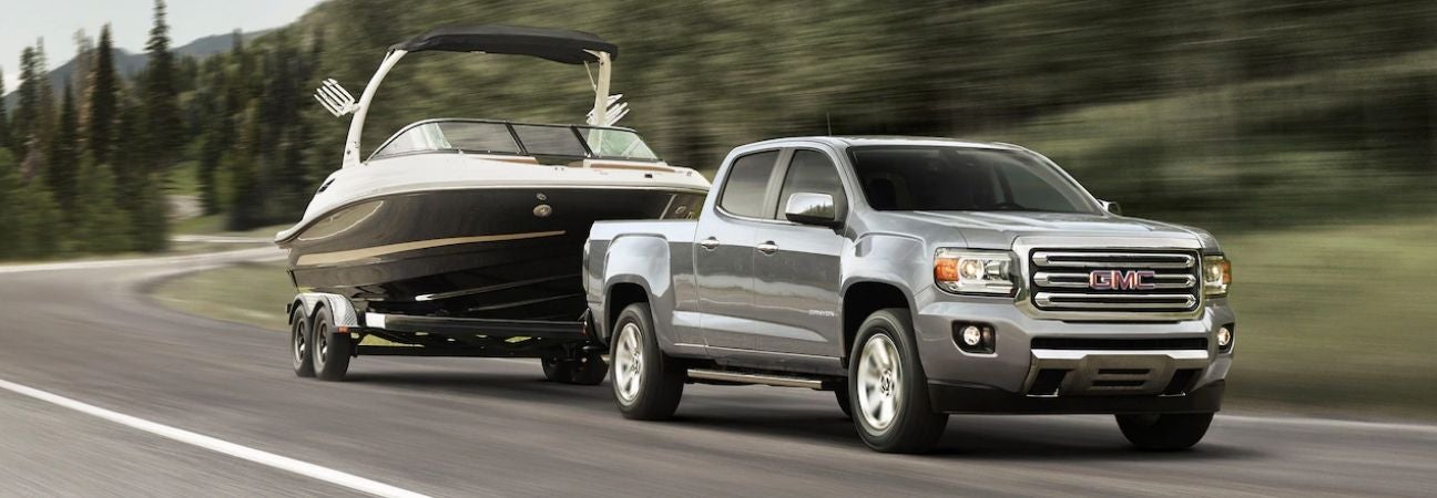 GMC Sierra hauling a boat down a winding road