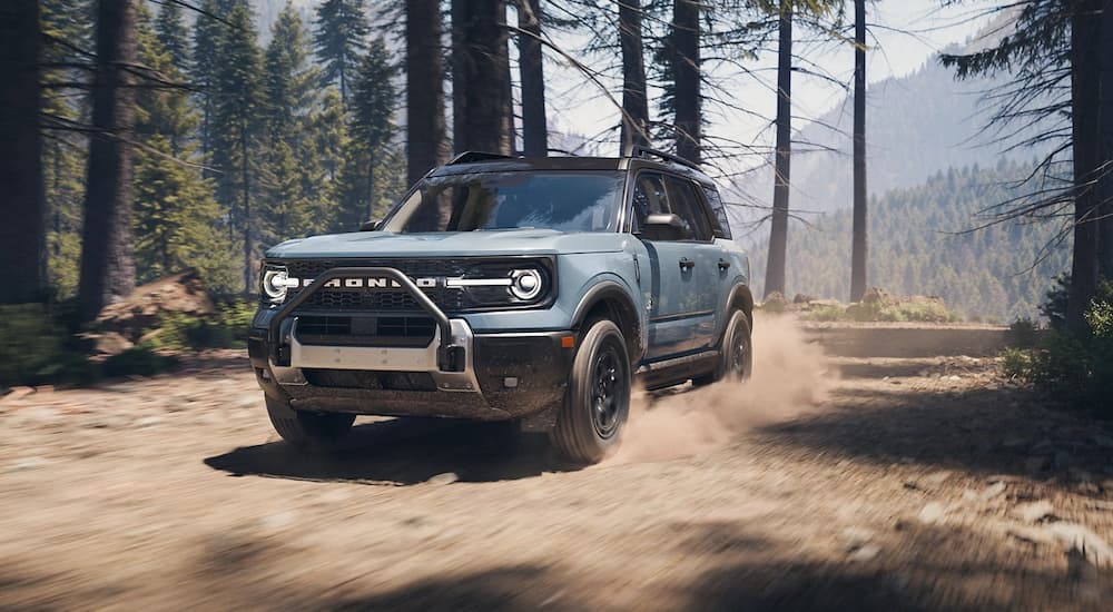 Blue 2025 Ford Bronco Sport for sale driving through a forest.