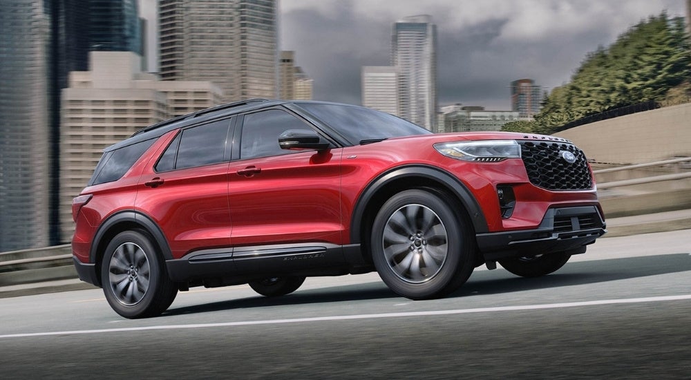 A red 2025 Ford Explorer ST-Line driving on a city street.