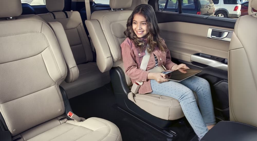 A young girl sitting in the back of a 2023 Ford Explorer at a used Ford dealer.