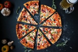 A fully sliced veggie pizza with a bite taken out of one of the slices. | St. Louis, MO