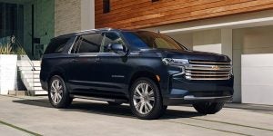 Profile view of a navy blue 2021 Chevy Suburban parked in front of a garage. | Chevrolet dealer in St. Louis, MO