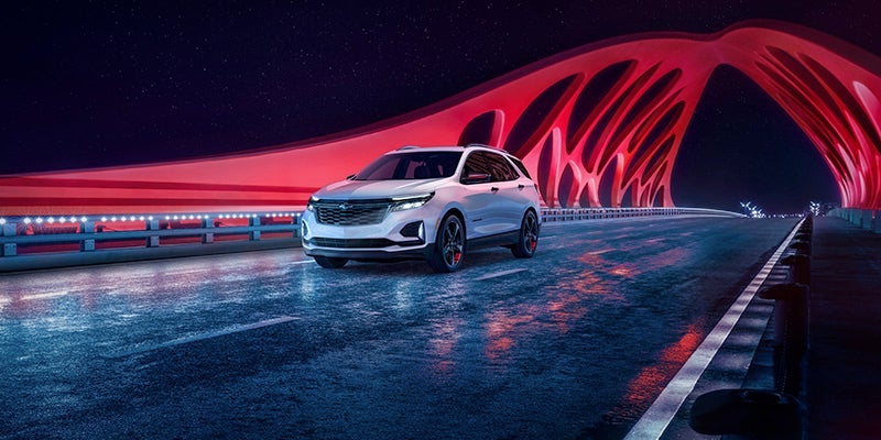 An all-new 2024 Iridescent Pearl Tricoat Chevy Equinox driving on a bridge. - Ted Britt Chevrolet Sterling, VA