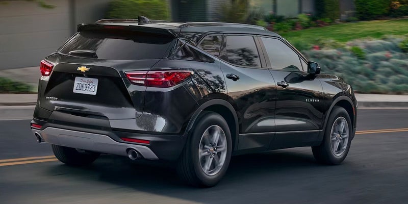 An all-new black 2024 Chevy Blazer driving down a suburban neighborhood street. - Ted Britt Chevrolet Sterling, VA