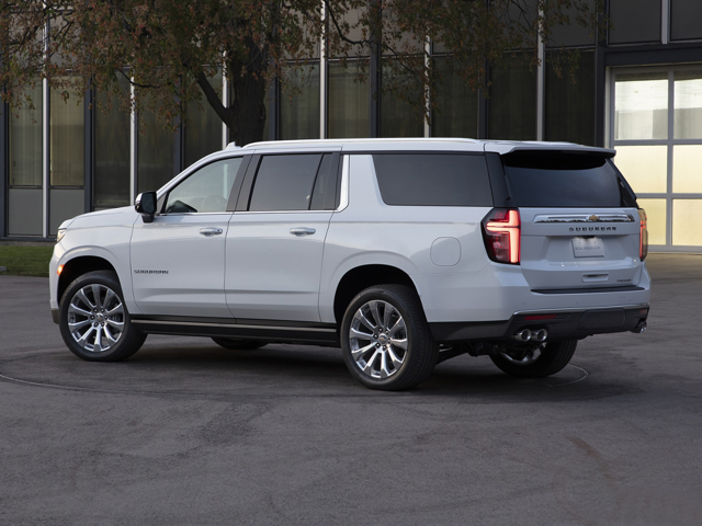 An all-new Summit White 2024 Chevrolet Suburban parked outside an office building in the parking lot in Sterling, VA.
