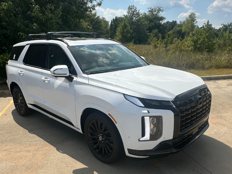 Front and side view of a white Hyundai Palisade parked near trees under a blue sky, ideal for fall road trips in Arkansas