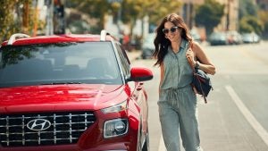 A woman walking toward a parked red 2022 Hyundai Venue. | Hyundai dealer in Little Rock, AR.
