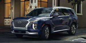 Front profile view of a dark blue 2022 Hyundai Palisade. parked in front of a building. | Hyundai dealer in Little Rock, AR.