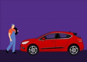 A service technician carrying a tire to a red car. | Car repair in Little Rock, AR.