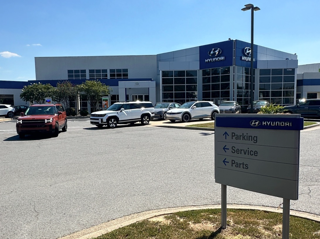 Front view of Crain Hyundai of Little Rock dealership with Hyundai vehicles parked out front and service sign in foreground
