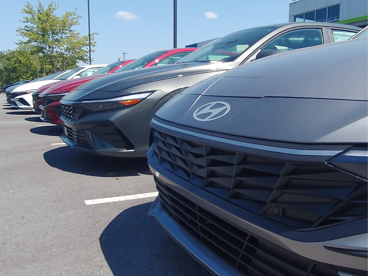 Close-up of new 2024 Hyundai sedans in various colors lined up in a row at Crain Hyundai of Little Rock, ready for test drives under a sunny sky.