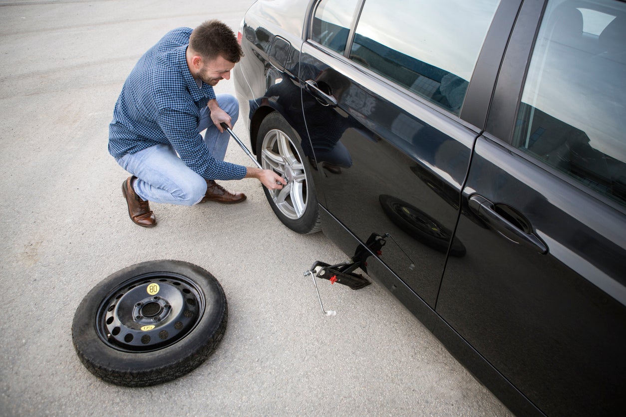 Man changing a flat tire on his KIA