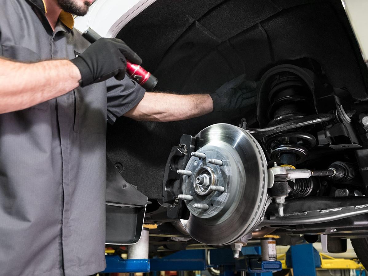 A mechanic performing a brake inspection on Dodge parts