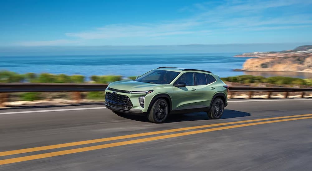 A green 2026 Chevy Trax driving on a highway.