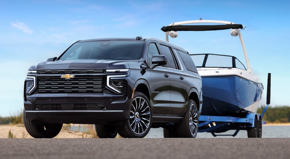 Black 2026 Chevy Suburban High Country towing a boat.