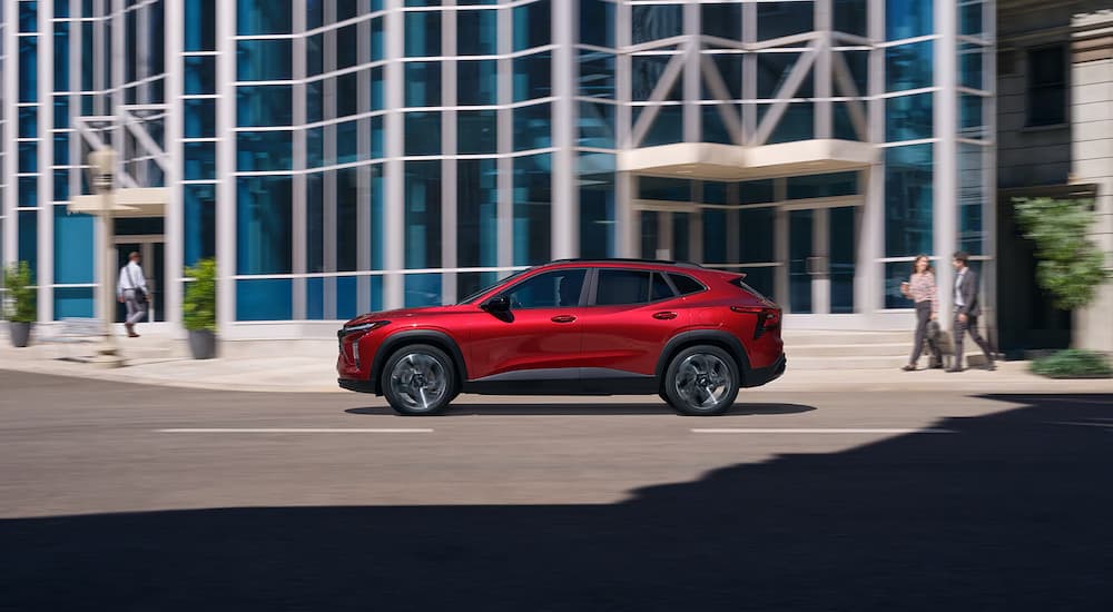 Side of a red 2026 Chevy Trax RS driving down a road.