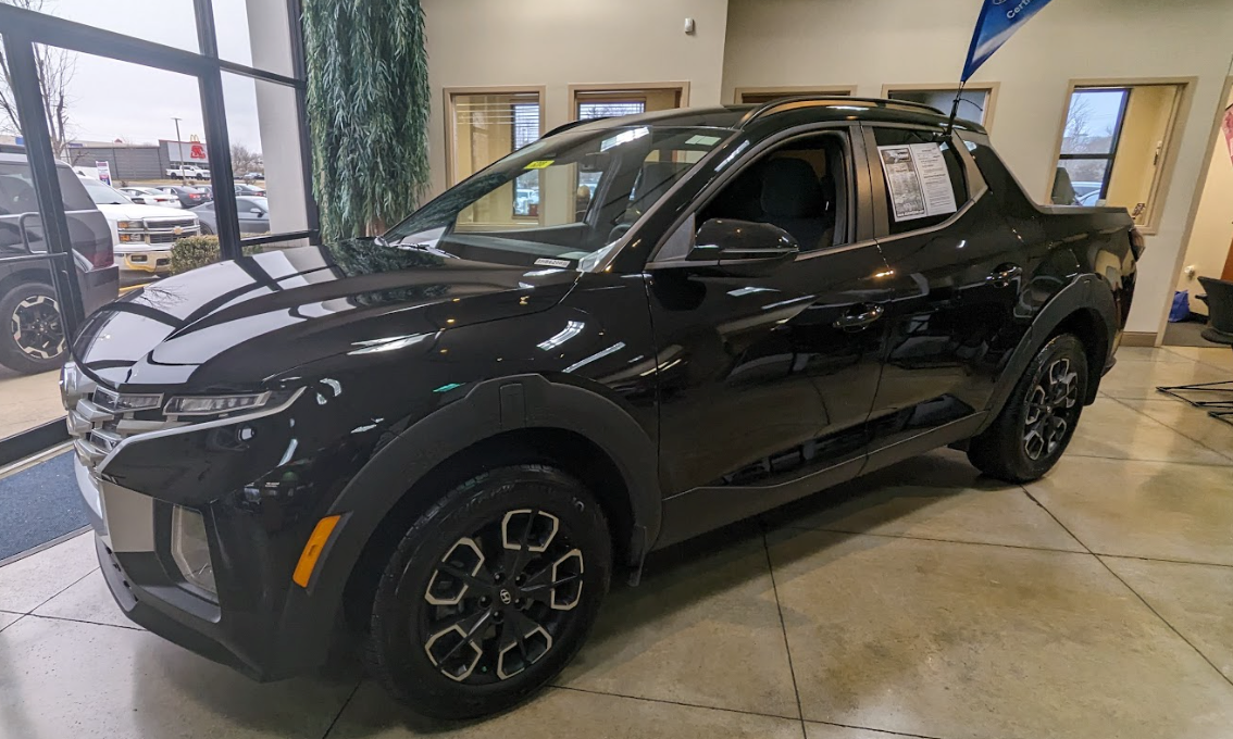 Black Hyundai Santa Cruz parked inside Crain Hyundai of Bentonville showroom with natural light reflecting off its freshly cleaned exterior.