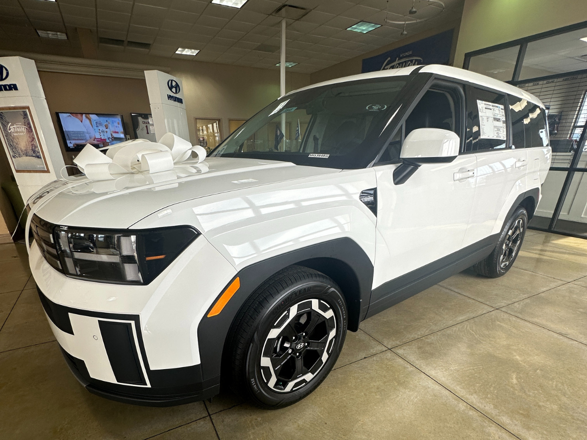 White Hyundai SUV with a gift bow showcased in the Crain Hyundai of Bentonville showroom, celebrating 2025 IIHS safety award recognition