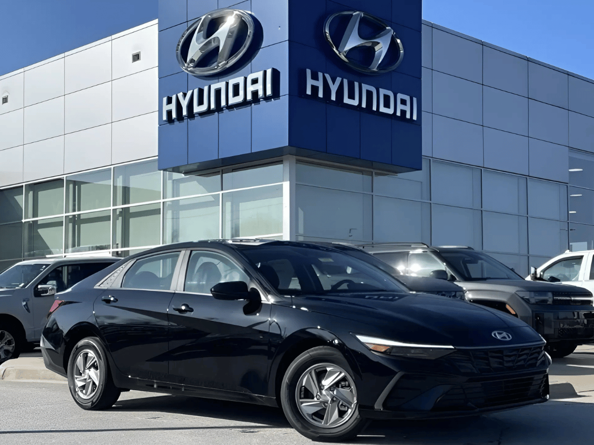 Black 2025 Hyundai Elantra parked in front of Crain Hyundai of Fayetteville dealership under clear skies.