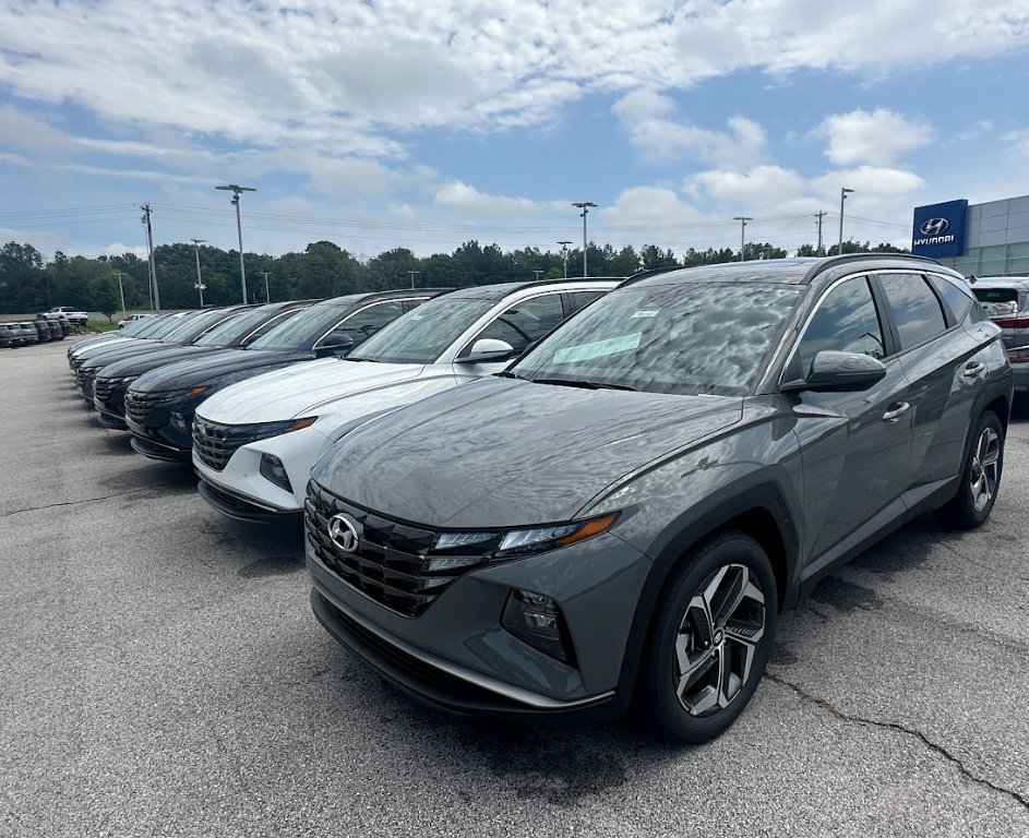 Lineup of Hyundai SUVs parked outside Crain Hyundai of Fayetteville under a partly cloudy sky