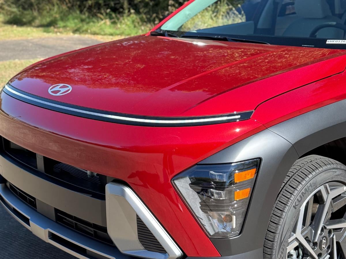 Close-up of a red Hyundai Kona SUV parked at Crain Hyundai of Fayetteville, highlighting the vehicle’s modern front design and advanced features.