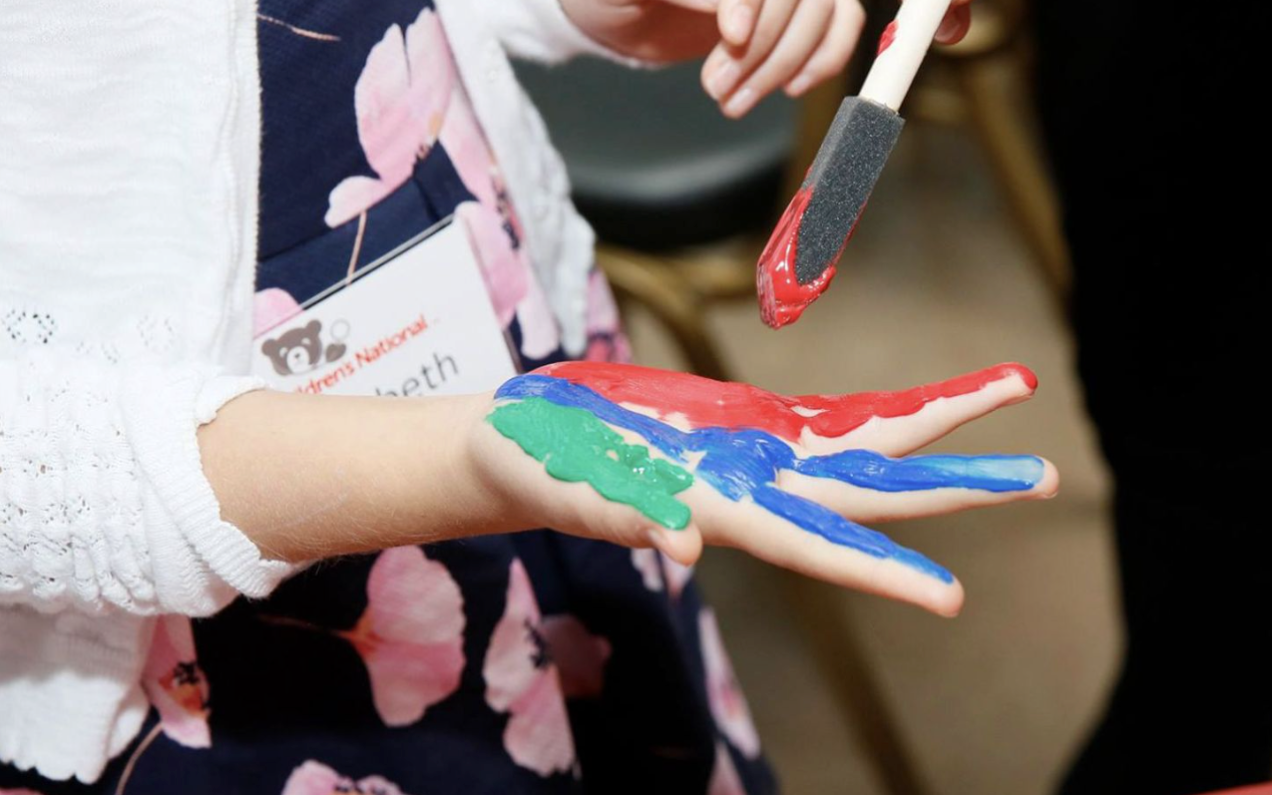 Child painting hand with red, green, and blue paint for Hyundai Hope On Wheels event