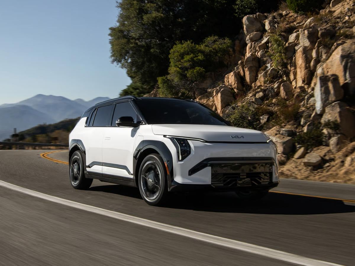 White 2027 Kia EV3 electric SUV driving on a scenic mountain road with modern styling and advanced technology