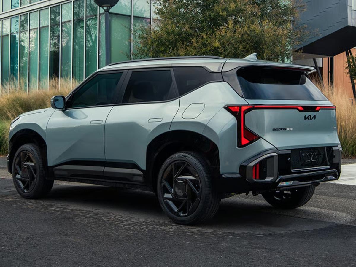Light gray 2027 Kia Seltos parked outside a modern building