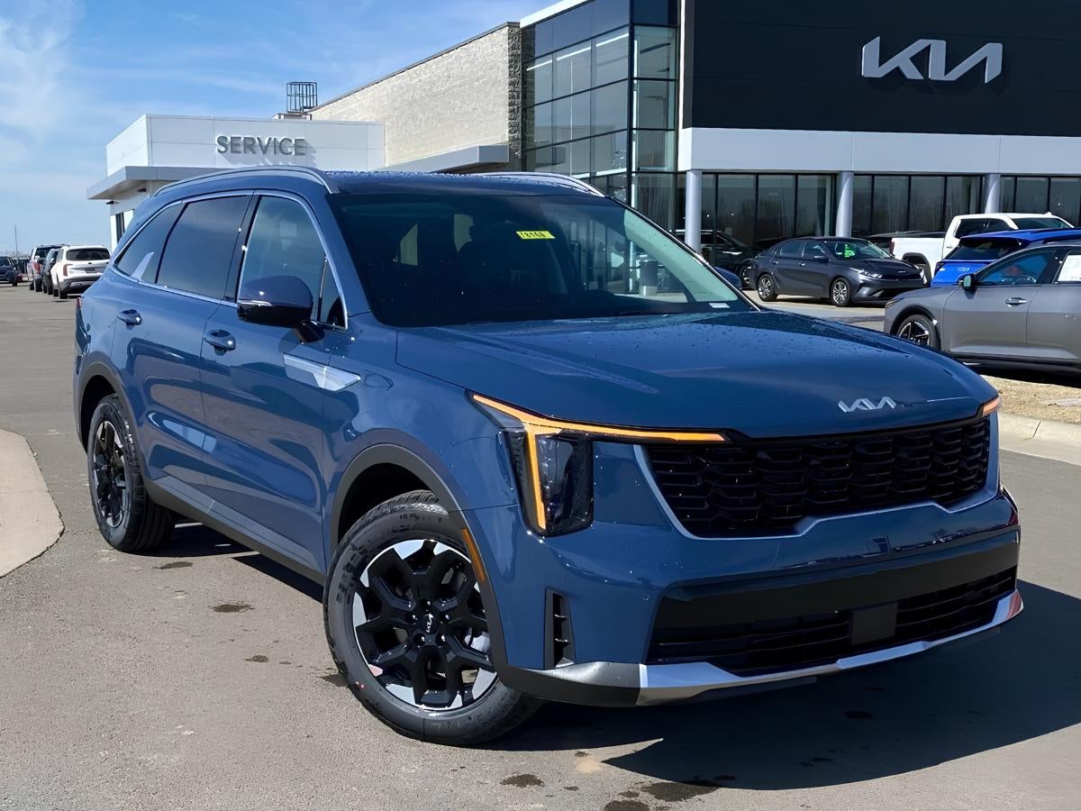 Blue Kia Sorento parked outside Crain Kia of Fayetteville dealership on a sunny day