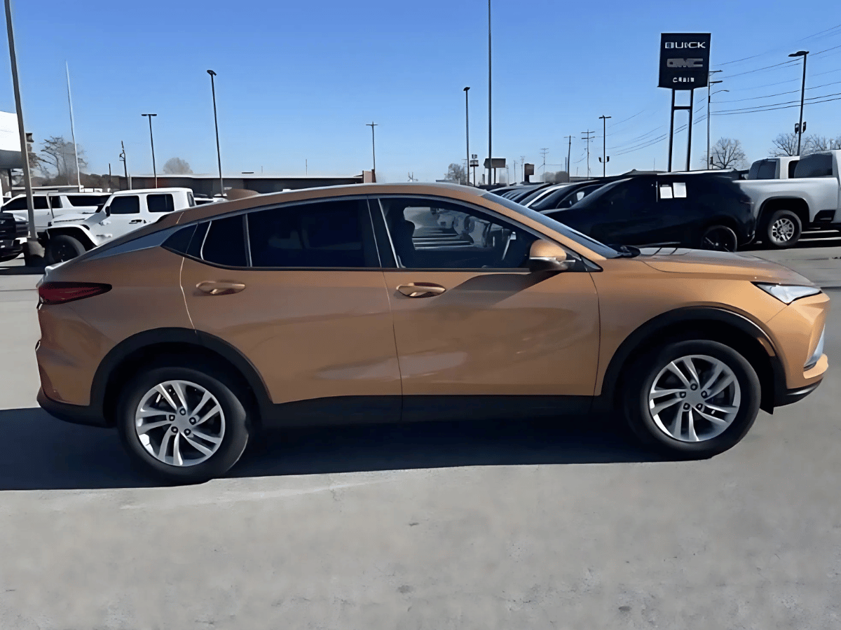 Side profile of the 2025 Buick Envista in bronze parked at Crain Buick GMC in Springdale, Arkansas, under clear skies