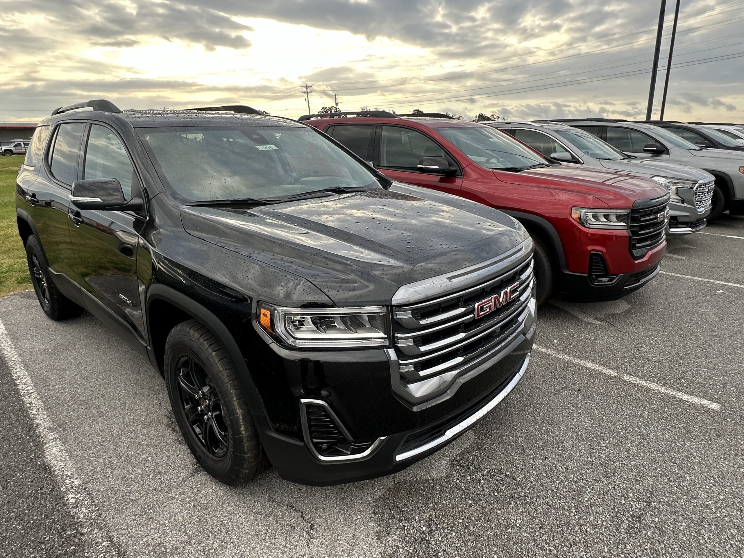 Row of new GMC SUVs including black and red models parked at Crain Buick GMC in Springdale, Arkansas