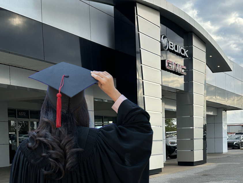 Graduate in cap and gown standing outside Crain Buick GMC in Springdale, Arkansas