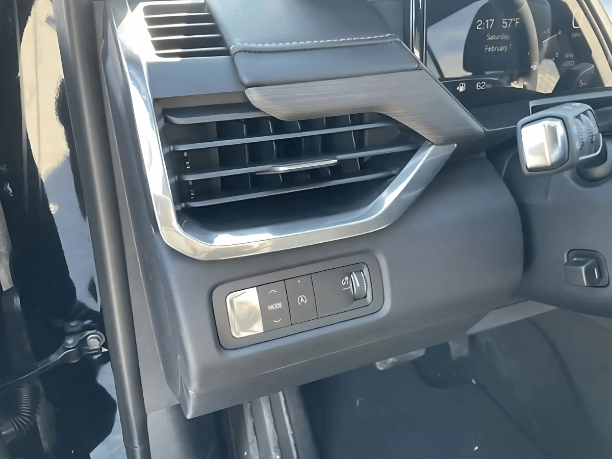 Close-up of 2025 GMC Acadia interior showing air vent and drive mode controls near the steering column with dashboard display