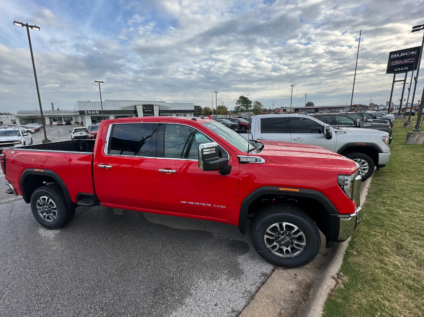 Side profile of a red GMC Sierra HD with Pro Safety Plus parked in front of Crain Buick GMC in Springdale, Arkansas
