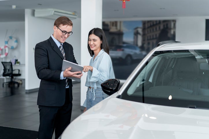 Woman in the showroom enjoying luxury car.