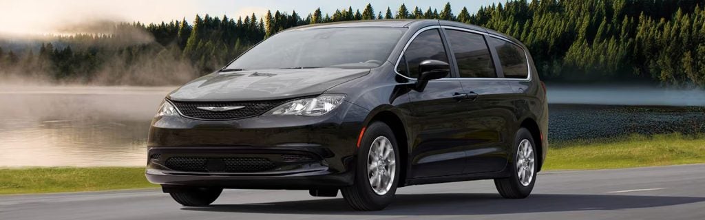 2026 Chrysler Voyager driving on a scenic road near a lake