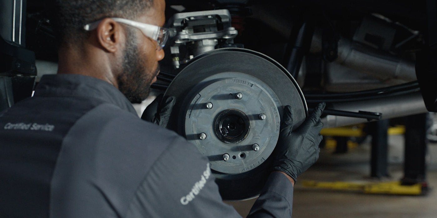 Technician holding a brake drum during a brake inspection in Graham, Texas