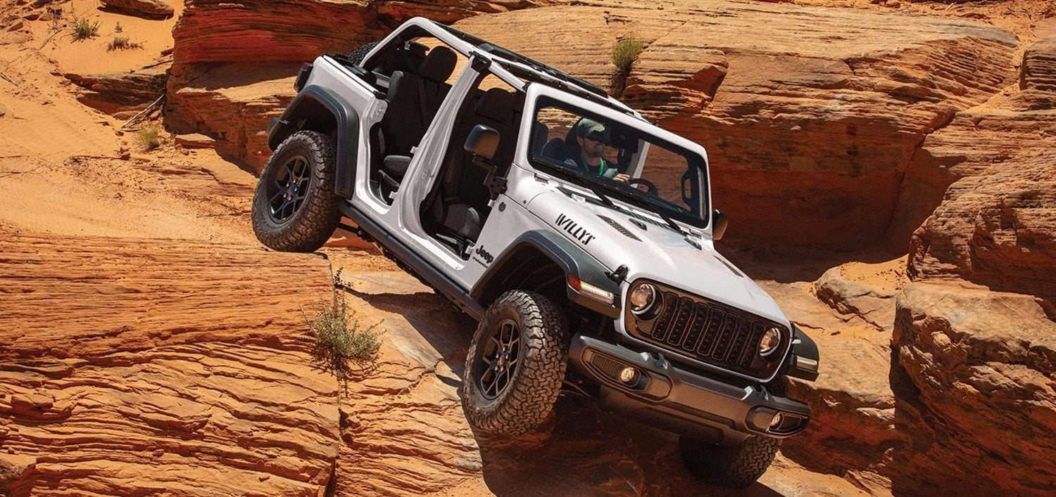 White 2026 Jeep Wrangler Willys with doors and top removed crawling down a trail
