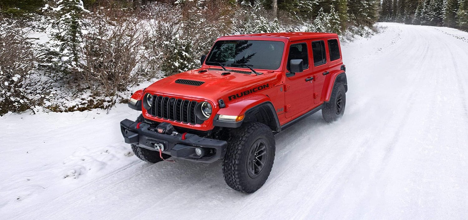 Red 2026 Jeep Wrangler Rubicon four door on a forest road