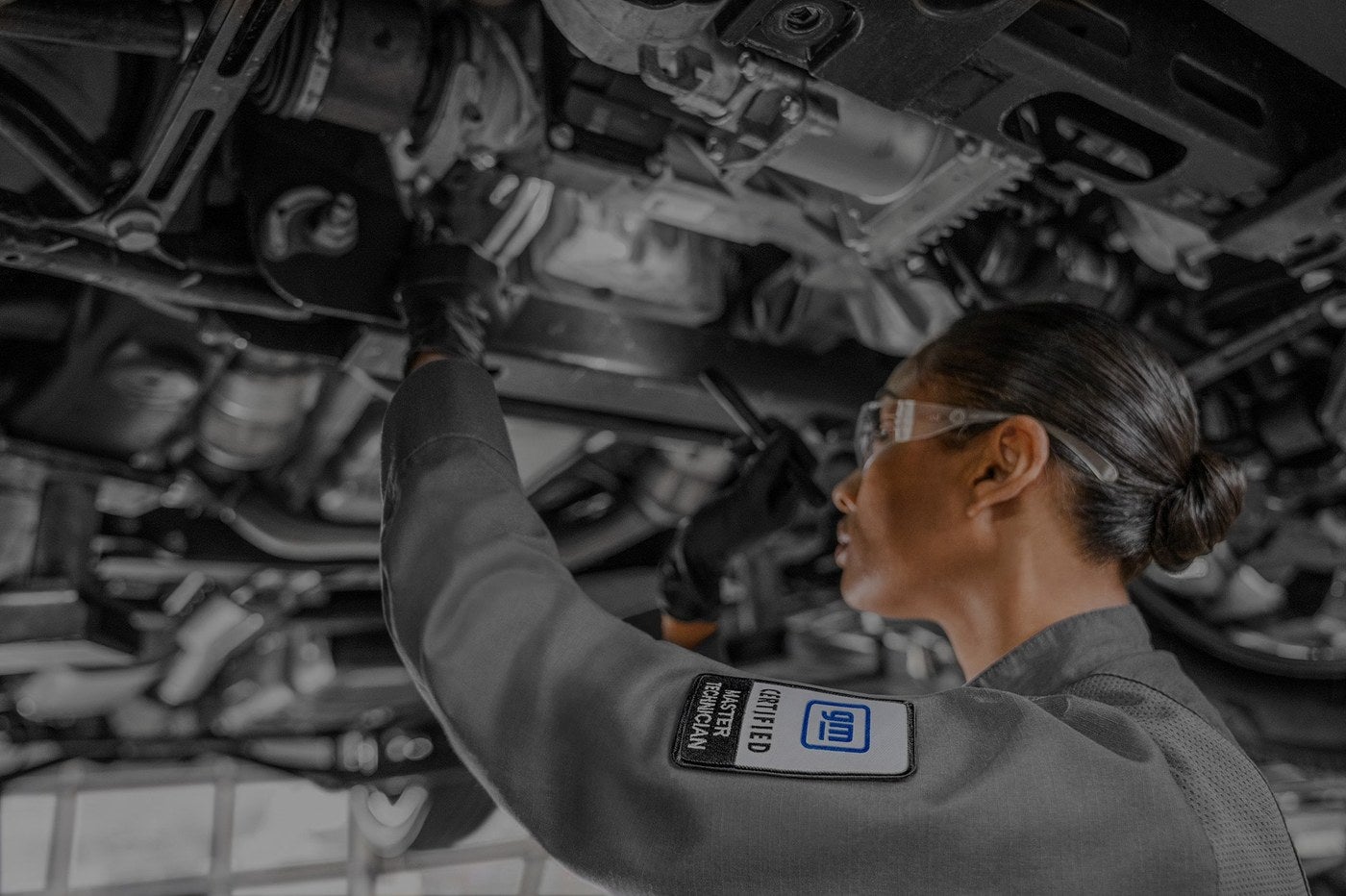 Technician reaching under a lifted GMC vehicle during a brake inspection in Graham, TX