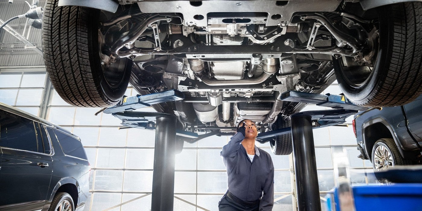 Technician inspecting the underside of a GMC SUV raised on a lift in Graham, TX