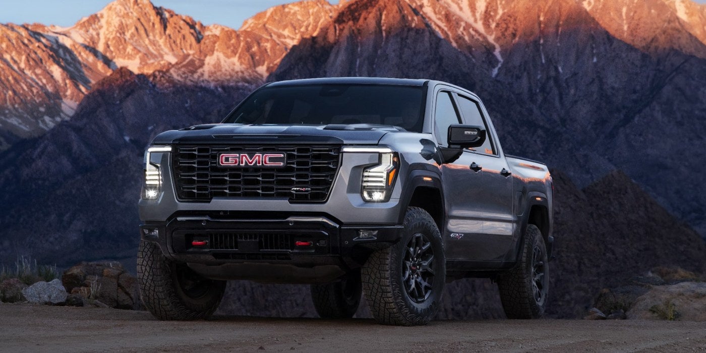 Gray GMC Sierra 1500 parked on a dirt road with mountains behind it